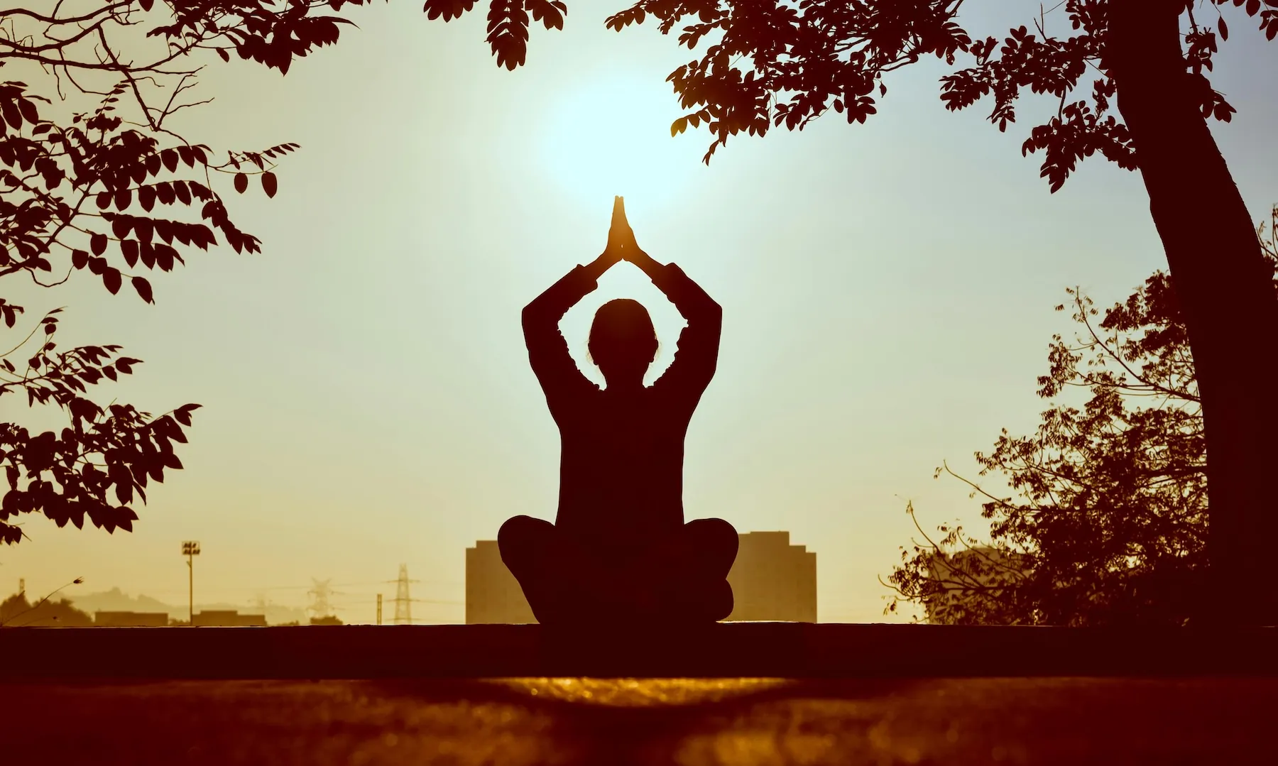 Free Silhouette of a person practicing yoga outdoors during sunrise, creating a calming atmosphere. Stock Photo
