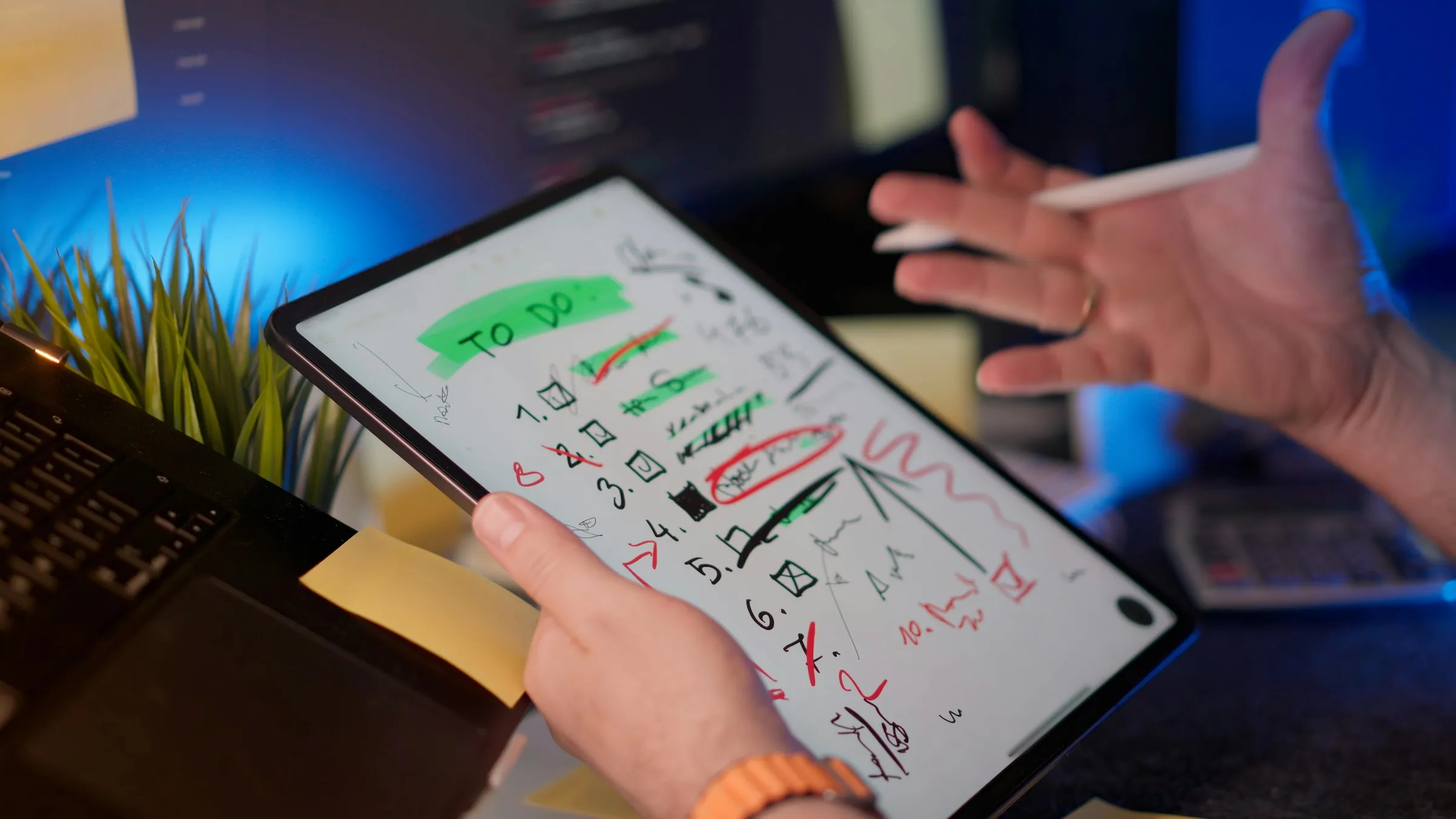 Free A person managing tasks on a tablet with a digital pen in a modern office setting. Stock Photo